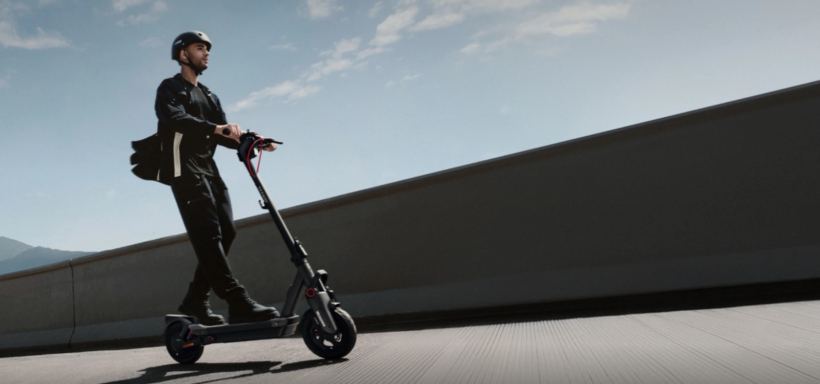 Mann med hjelm kjører en Segway Ninebot Max G3 elsparkesykkel i dagslys